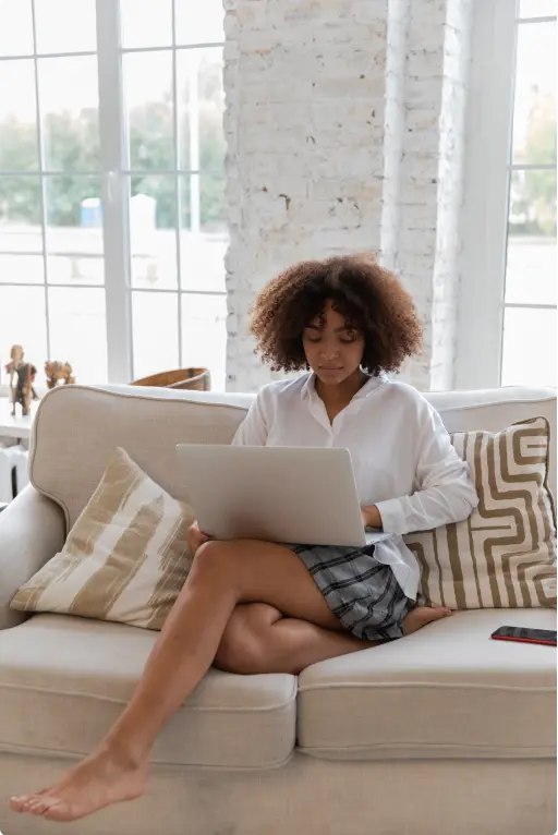 Woman in front of a laptop sitting on a couch